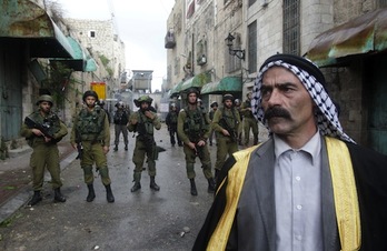 Un hombre pasa frente a un grupo de soldados israelíes en Hebrón, en la Cisjordania ocupada. (Hazem BADER/AFP PHOTO) 