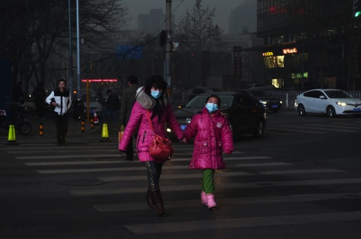 Una madre camina con su hija por las calles de Pekín. (Greg BAKER/AFP)