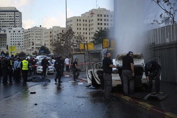 Agentes israelís analizan el coche mientras el cuerpo del palestino permanece cubierto a poco metros. (Menahem KAHANA / AFP)
