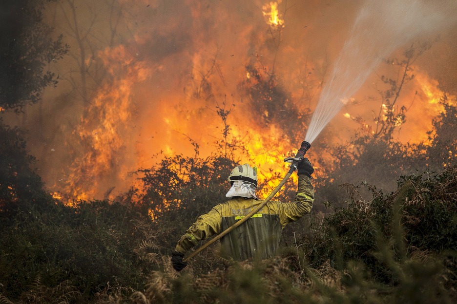 Un bombero hace frente a las llamas armado con su manguera. (Aritz LOIOLA / ARGAZKI PRESS)