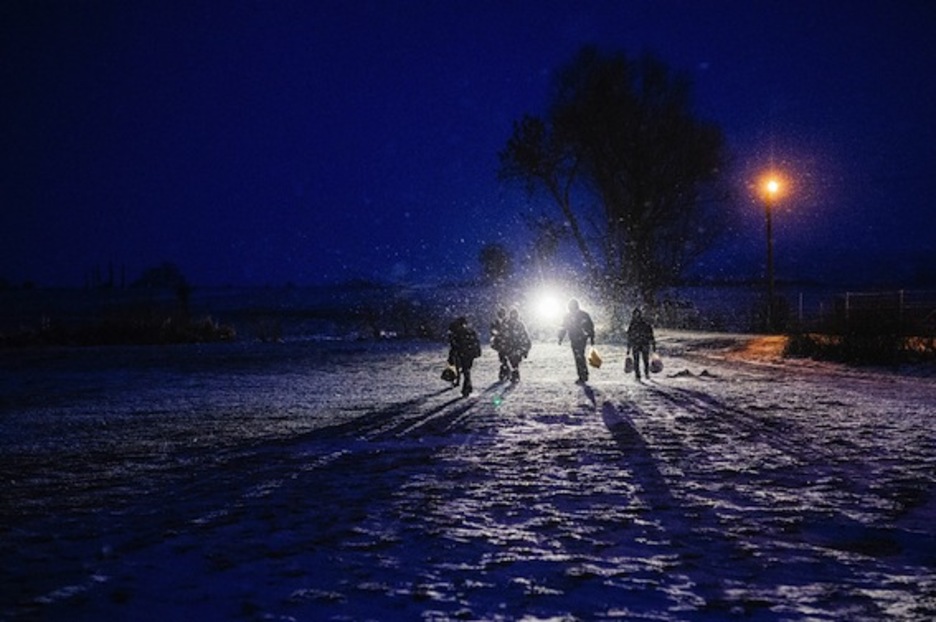Refugiados avanzan en la noche entre la nieve en Miratovac, en la frontera entre Macedonia y Serbia. (Dimitar DILKOFF/AFP)