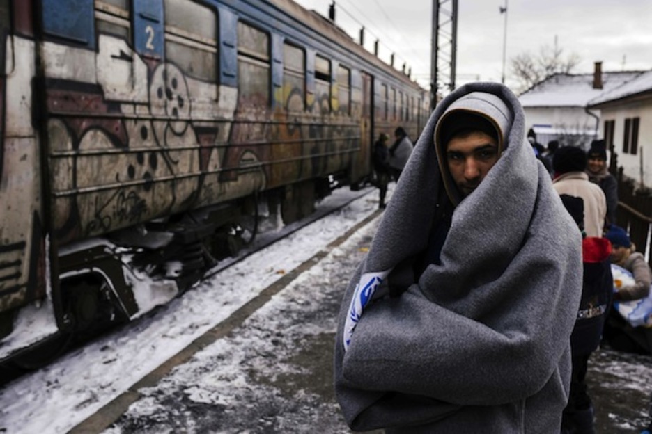 Un joven envuelto en una manta aguarda a un tren que le lleve a la frontera con Croacia. (Dimitar DILKOFF/AFP)