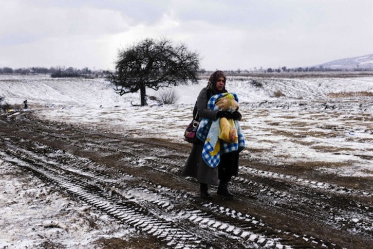 Una mujer camina entre la nieve, con un bebé en brazos, en la zona fronteriza entre Macedonia y Serbia. (Dimitar DILKOFF/AFP)