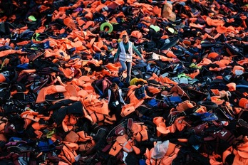 Dos voluntarias caminan entre chalecos de refugiados que han llegado a Lesbos. (Aris MESSINIS/AFP)