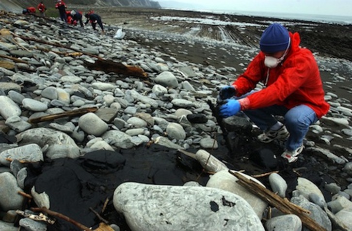 Un voluntario retira chapapote al pie de los acantilados de Zumaia. (Juan Carlos RUIZ / ARGAZKI PRESS)