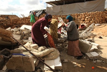 Emakume talde bat suntsitutako etxeen hondakinen artean ondasunak bilatzen. (Hazem BADER/AFP) 
