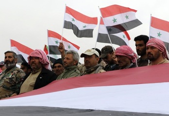 Voluntarios oficialistas celebran con banderas de Siria el final de sus entrenamientos. (LOUAI BESHARA / AFP) 
