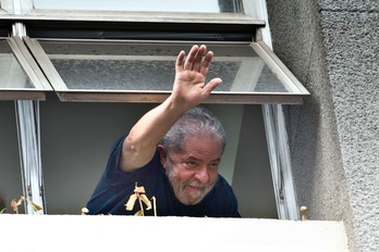 Lula da Silva saluda desde la sede del Partido de los Trabajadores tras abandonar la comisaría. (Nelson ALMEIDA/AFP) 