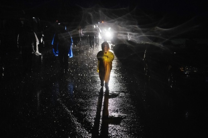 Una niña camina entre la lluvia en Idomeni, en la frontera entre Grecia y Macedonia. (Dimitar DILKOFF/AFP)