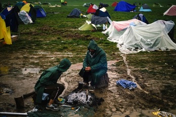 Dos personas tratan de calentar algo con lo que alimentarse en las proximidades de la frontera greco-macedonia. (DIMITAR DILKOFF  / AFP)