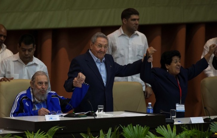 Raúl Castro alza la mano de su hermano Fidel en la ceremonia de clausura del séptimo congreso general del PCC. (Ismael FRANCISCO/AFP)