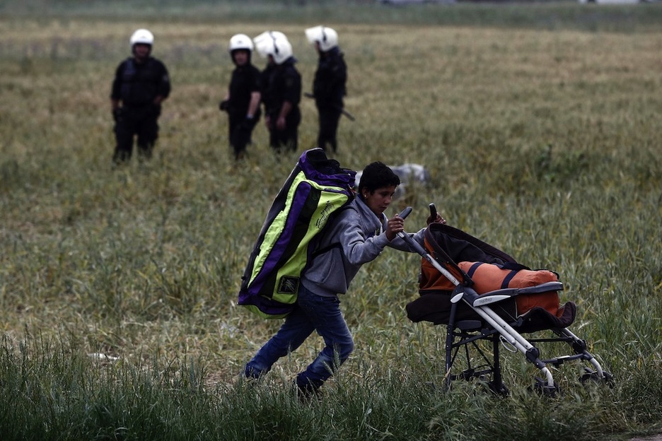 Una mujer abandona junto a su hijo el campamento de Idomeni. (Yannis KOLESIDIS / AFP)