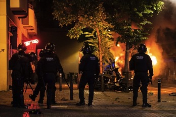 Los Mossos observa las llamas con las porras en la mano. (AFP)