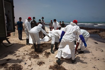 Ilargi Erdi Gorriko kideak, etorkin baten gorpua estaltzen Libiako hondartza batean. (AFP)