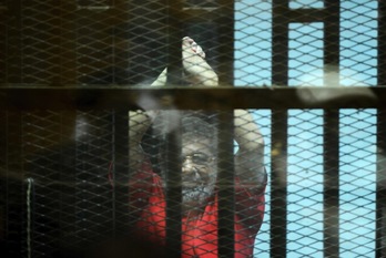 Mohamed Morsi levanta los brazos durante el juicio. (Mohamed EL-SHAHED/AFP)