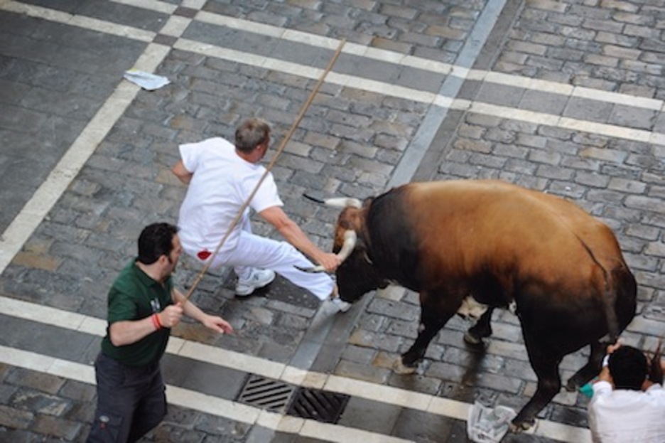 El corredor que intenta apartar al toro pasa por apuros al resbalar. (Jon URBE/ARGAZKI PRESS)
