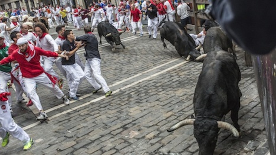Mientras unos toros empiezan a correr, otros patinan al llegar a la curva de Estafeta. (Lander ARROYABE/ARGAZKI PRESS)