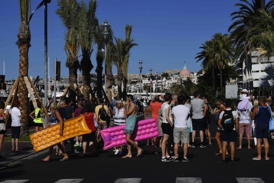 Dos personas se dirigen a la playa mientras decenas observan el camión empleado para el ataque. (ANNE-CHRISTINE POUJOULAT / AFP) Dos personas se dirigen a la playa mientras decenas observan el camión empleado para el ataque. (ANNE-CHRISTINE POUJOULAT / AFP)