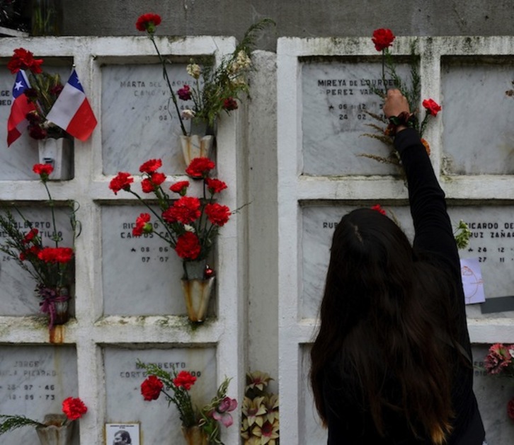 Una mujer deposita flores en un cementerio en el 43 aniversario del golpe de Estado de Pinochet. (Martin BERNETTI/AFP)