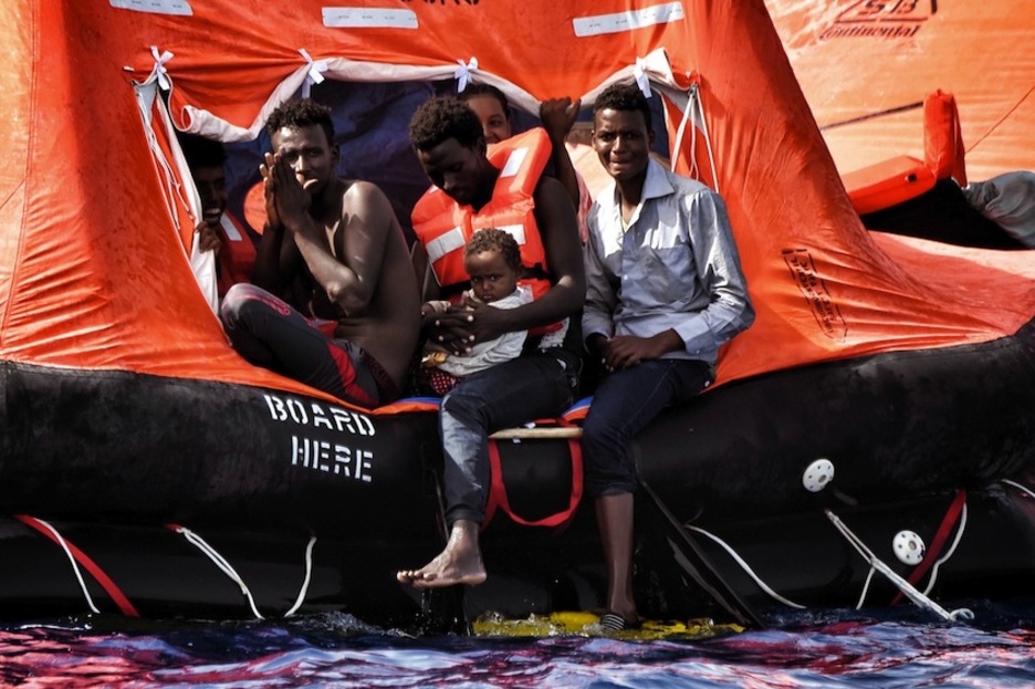 Tres hombres esperan, uno de ellos con un menor en brazos. (Aris MESSINIS / AFP) Tres hombres esperan, uno de ellos con un menor en brazos. (Aris MESSINIS / AFP)