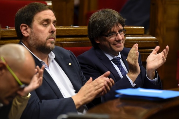 El president, Carles Puigdemont, junto a Oriol Junqueras, en una imagen anterior en el Parlament. (Josep LAGO/AFP)