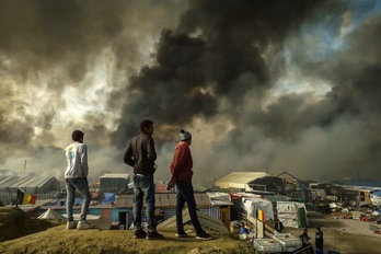 Inmigrantes observan la humareda que sale de La Jungla. (Philippe HUGUEN / AFP) 