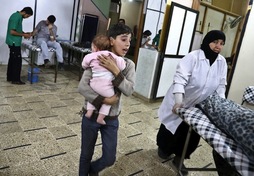 Un niño correo con un bebé en brazos en un hospital tras un ataque aéreo en Duma. (Abd DOUMANY/AFP)
