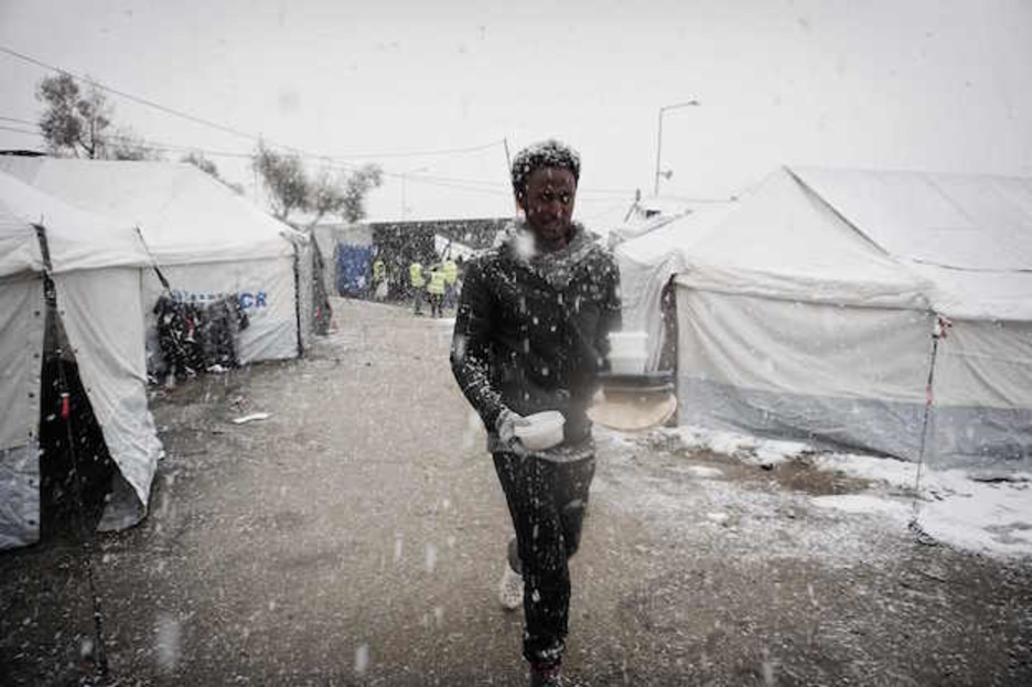 Un hombre camina con su ración de comida en un campo de refugiados en la isla de Lesbos, Grecia. (AFP PHOTO / STR)