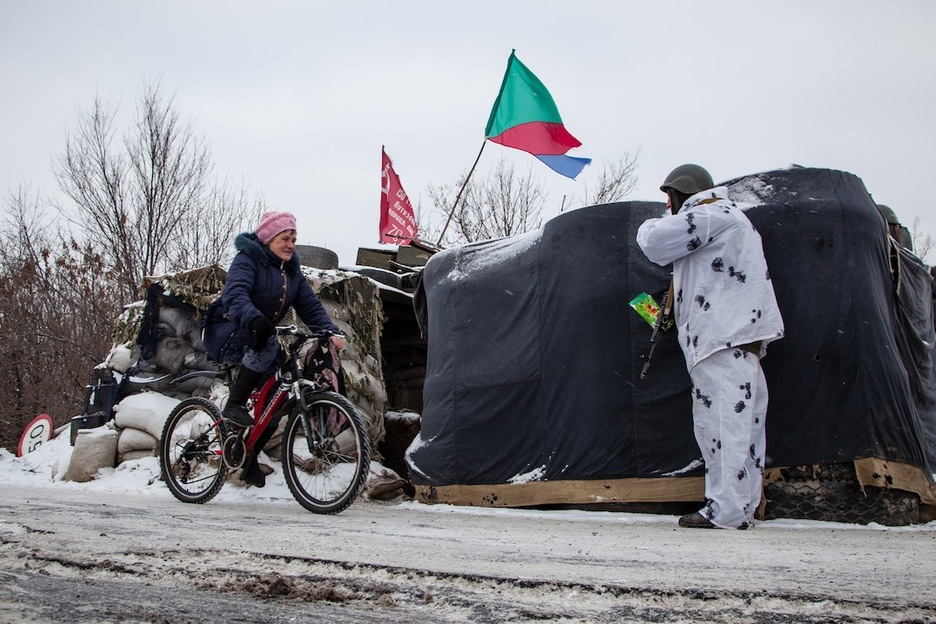 Una mujer cruza en bicicleta un puesto de control. De otra manera, debería hacer varios kilómetros a pie en pleno invierno. (Juan TEIXEIRA)