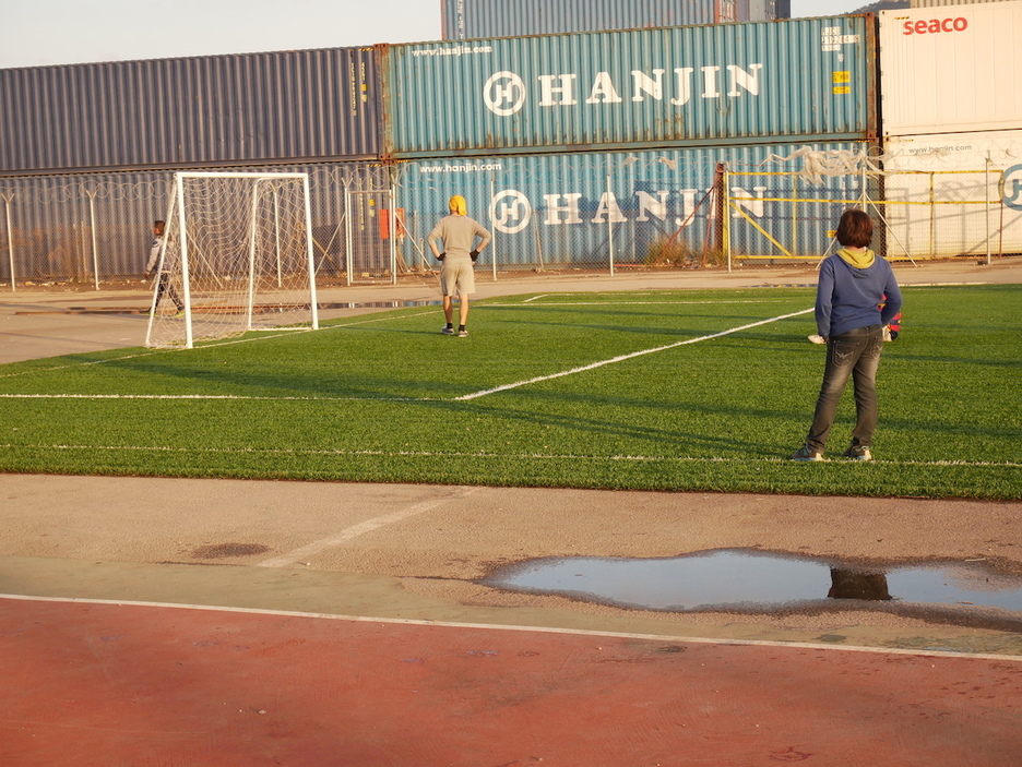 Junto a los containers de carga del puerto, un campo de fútbol habilitado en Skaramangas.  