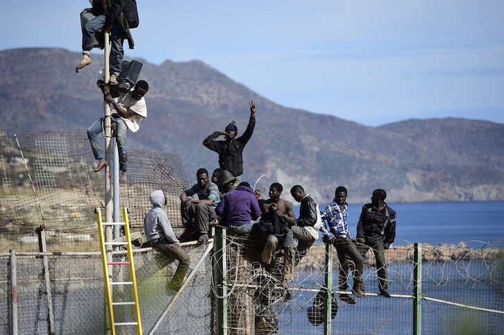Inmigrantes subidos a una valla en la frontera española. (Alexander KOERNER / AFP)