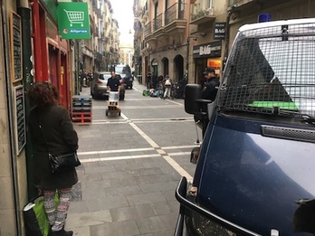 Los ocupantes de la vivienda de San Antón de Iruñea van sacando sus enseres, mientras la calle permanece cortada por dos furgonetas de la Policía española.