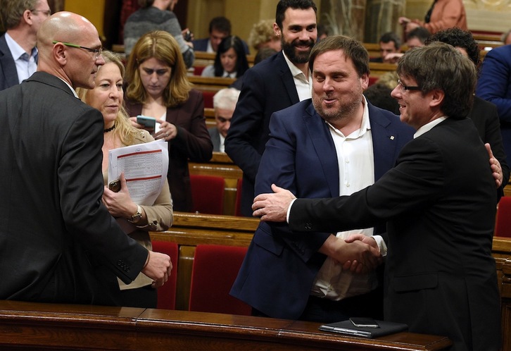 Junqueras y Puigdemont se saludan tras la aprobación de los presupuestos. (Lluis GENE / AFP)