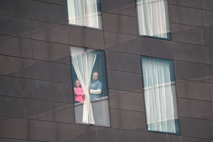 Dos vecinos de un edificio cercana al Manchester Arena miran por la ventana. (Oli SCARFF/AFP PHOTO)