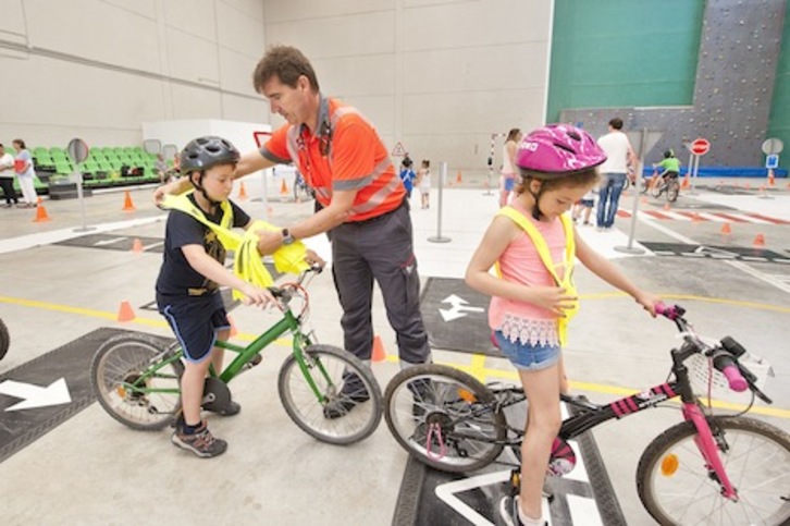 Un agente de la Policía Foral coloca el chaleco a un niño en el circuito de educación vial. (GOBIERNO DE NAFARROA)