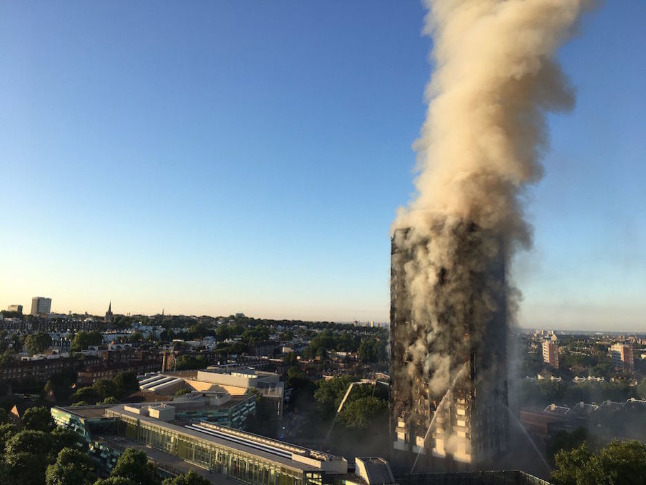 Los bomberos trabajan con sus mangeras mientras la torre desprende una gran humareda. (NATALIE OXFORD / AFP)