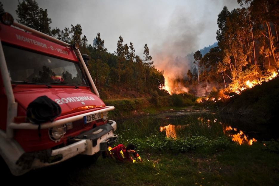Un bombero descansa junto a su camión mientras observa el incendio. (Patricia DE MELO/AFP)