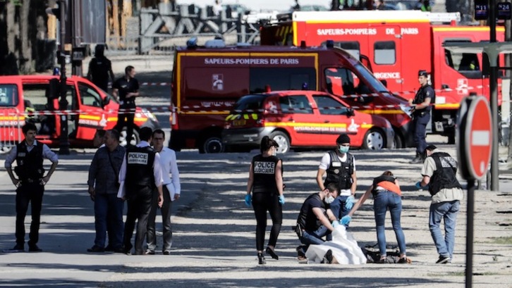 Efectivos de la Policía Judicial junto al cadáver del hombre que ha impactado su coche contra un furgón policial. (Thomas SAMSON/AFP)