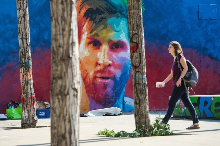 Una mujer pasea ante un graffiti de Messi pintado en Barcelona. (Josep LAGO/ARGAZKI PRESS)