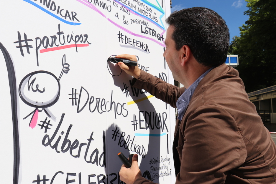 El portavoz foral de Gipuzkoa, Imanol Lasa, escribe en el mural colocado con motivo del Día del Orgullo LGTBI. (Gipuzkoako Foru Aldundia)