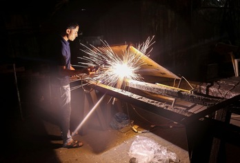 Un palestino trabaja en Gaza durante las pocas horas de luz que disponían hasta ayer. (Said KHATIB/AFP)