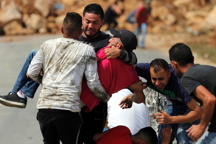 Jóvenes palestinos evacúan a uno de los heridos en las protestas. (Abbas MOMANI/AFP)