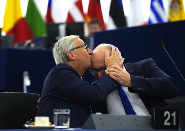 El presidente de la CE, Jean-Claude Juncker, besa al vicepresidente,  Frans Timmmermans, en el pleno celebrado en Estrasburgo. (Patrick HERTZOG/AFP)  