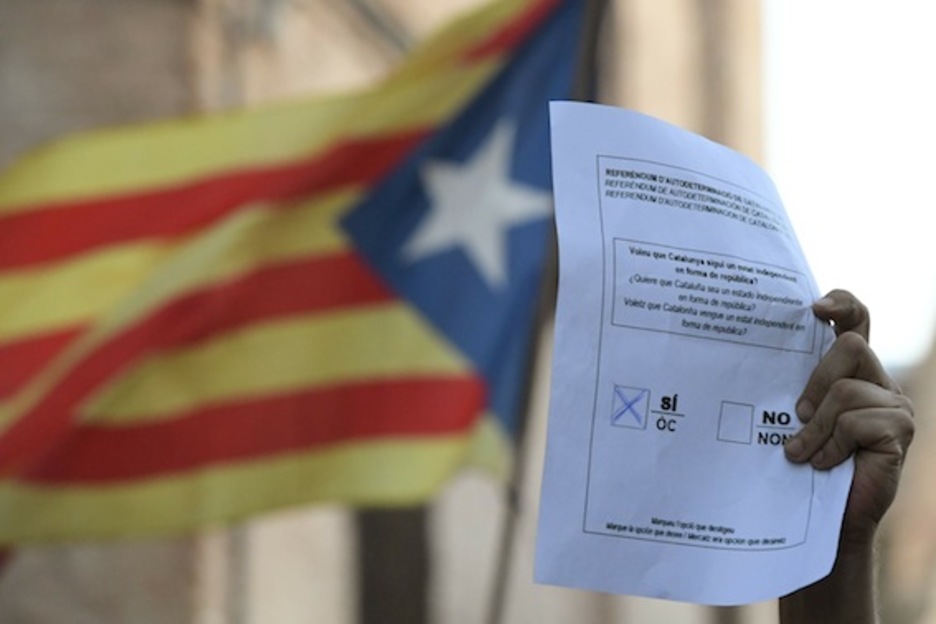 Uno de los congregados sostiene una papeleta del 1-O. (Josep LAGO/AFP)