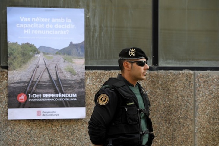 Un guardia civil, junto a un cartel por el ‘Sí’, pocos días antes del referéndum del 1 de octubre del pasado año. (Josep LAGO/AFP)