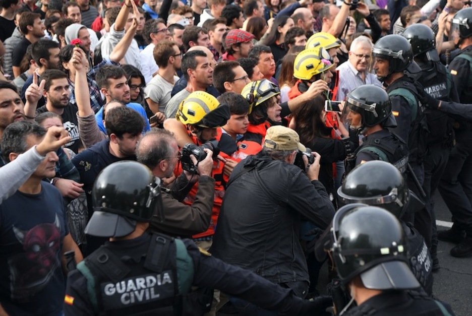 Los bomberos hacen barrera entre la Guardia Civil y la multitud en un colegio de Barcelona. (Lluís GENE/AFP)