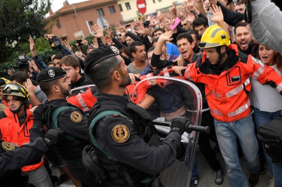 Los bomberos han formado un cordón de seguridad entre los ciudadanos y la GC en Sant Julià de Ramis. (Lluís GENÉ/AFP)