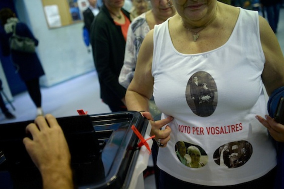 Una mujer acude a votar con la foto de sus familiares impresa en la camiseta: «voto por vosotros». (Josep LAGO/AFP)