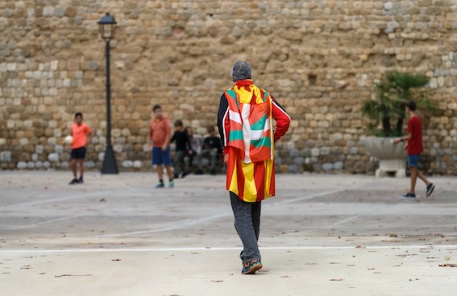 Un hombre camina con una estelada y una ikurriña a la espalda en Lladó, Girona. (César MANSO/AFP)