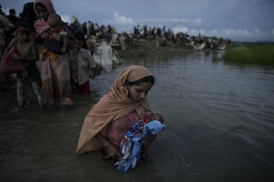 Una refugiada cruza el río Naf con su bebé en brazos. (Fred DUFOUR/AFP)